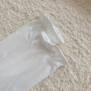 Detailed close-up of white knitted socks featuring elegant ruffled edge on soft carpet