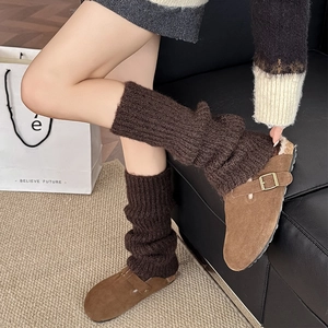 Close-up of dark brown ribbed knit leg warmers with suede slippers for a cozy winter look
