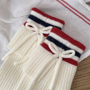 Close-up of ribbed knit leg warmer with red and blue stripes and a decorative bow