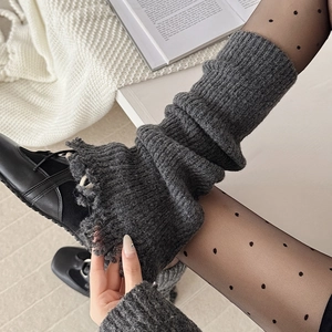 Close-up of dark grey knitted leg warmers with distressed fringe details and chunky texture