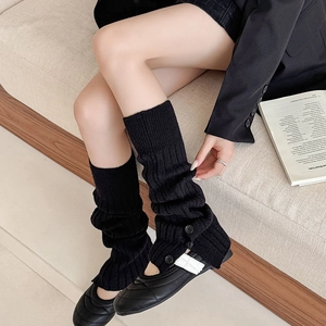Detail of black ribbed knit leg warmers with side buttons and stylish slouchy texture