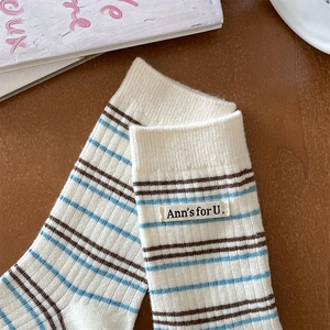 Détail de chaussettes rayées en cachemire avec étiquette tissée sur fond en bois