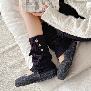 Detail of cable knit leg warmers with wood buttons and fuzzy slippers in a cozy home setting