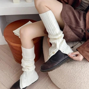 Detail view of cream rib-knit leg warmers with button side split over leather boots