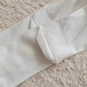 Macro detail of white ballet style split-toe calf socks with breathable knitted texture