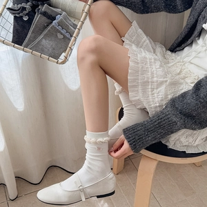 Detail of white cotton mid-calf socks with heart embroidery and ruffled knit cuff