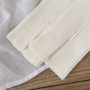Detailed macro view of white ribbed knit leg warmers showing the slit hem and soft texture