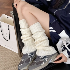 Close-up of cream-colored cable-knit leg warmers showing soft thick ribbed texture