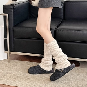 Detail of ribbed knit leg warmers in off-white paired with grey felt buckle slippers