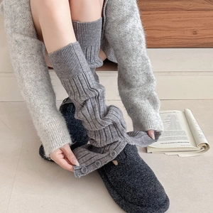 Detail of grey ribbed knit leg warmers with decorative side buttons and split hem