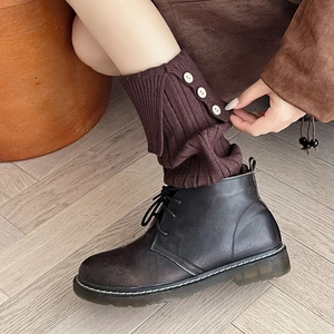 Detail of dark brown ribbed knit leg warmers with three side buttons and split cuff design