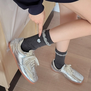 Dark gray ribbed mid-calf socks with wavy edges and heart embroidery worn with silver shoes