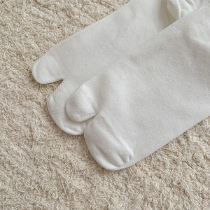 Close-up of white tabi socks featuring a classic split-toe design and knitted cotton texture