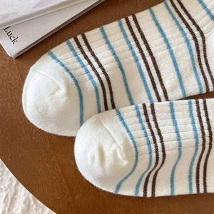 Détail de chaussettes en cachemire rayées montrant la maille sur fond en bois chaud