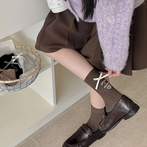 Detail of brown cotton calf socks featuring white ribbon bow and heart embroidery motifs