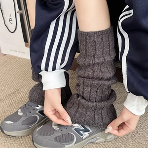 Detail of dark grey cable knit leg warmers showing thick texture and slouchy winter style