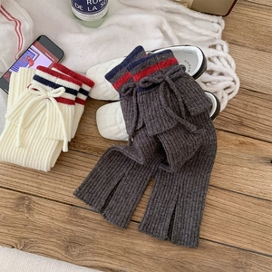 Close-up of knitted leg warmers with red and blue stripes and drawstring bow details
