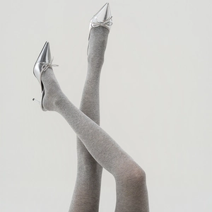 Detailed texture of gray knit tights paired with silver bow high heels on gray background
