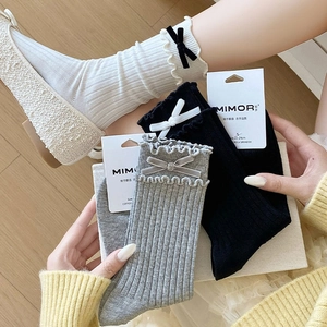 Detail of ruffle cuff cotton socks featuring velvet bows in black, white and grey