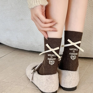 Detail of dark brown knit mid-calf socks with white ribbon bow and heart embroidery