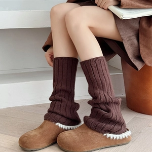 Close-up of ribbed knit leg warmers paired with cozy shearling-lined suede slippers