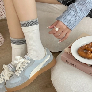 Chaussettes bleues à rayures chic avec baskets rétro sur un sol en bois clair