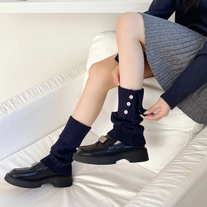 Detailed knit texture of dark blue leg warmers featuring vintage side buttons and vertical ribs