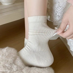 Close-up of elastic ribbed texture and creamy beige knit fabric on mid-calf socks