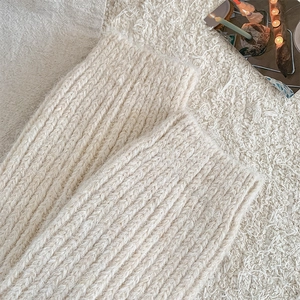 Detailed close-up of cream white ribbed knit leg warmers with thick winter texture