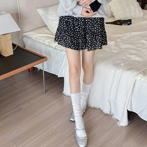 Detail showing high-waisted black floral ruffled mini skirt made of lightweight chiffon fabric