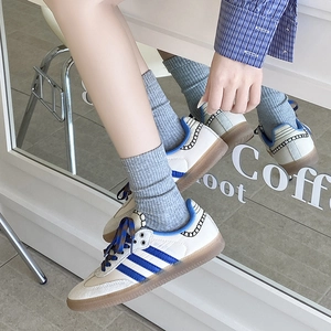 Detail of cream suede sneakers with blue stripes paired with ribbed cotton mid-calf socks