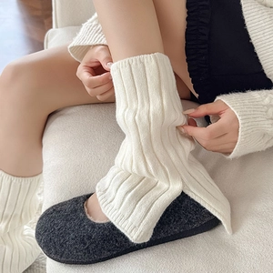 Close-up of cream white ribbed knit leg warmers with side slit detail and thick texture