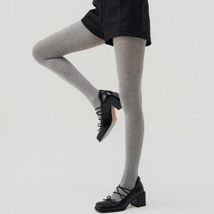 Detail of grey ribbed knit tights paired with black Mary Jane shoes on a clean background