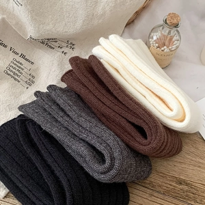 Detailed close-up of folded ribbed knit leg warmers in white, brown, grey, and black