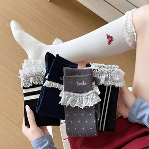 Detail of lace trim and alphabet embroidery on cotton calf-high socks for girls