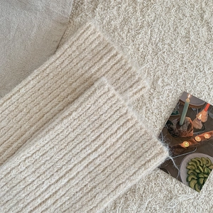 Detailed macro view of the cream white ribbed knit leg warmer with soft wool texture