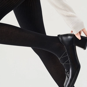 Close-up of black ribbed tights with shiny Mary Jane block heels and cross straps
