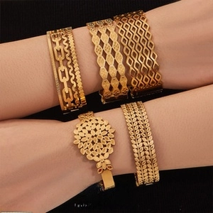 Close-up of gold-plated bracelets featuring hollow geometric and sunflower leaf patterns