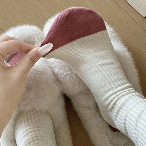 Detail of cream rib-knit mid-calf socks with burgundy toe stitching and high elasticity