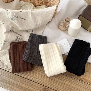 Detail of ribbed knit leg warmers in various colors stacked on a wooden surface