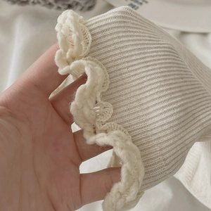 Détail de chaussettes en maille côtelée blanc cassé avec bords à volants délicats