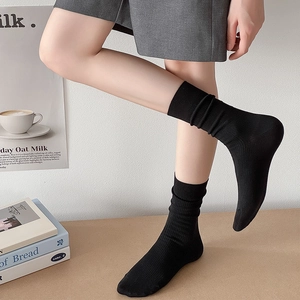 Gros plan de chaussettes mi-mollet côtelées noires dans un décor de style de vie épuré