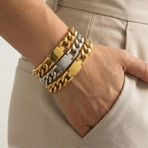Detailed view of layered 18K gold and silver plated Cuban link bracelets on a wrist
