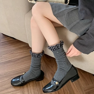 Detail of gray ribbed mid-tube socks with plaid ruffle trim and black patent leather shoes