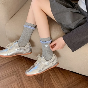 Detail of grey crew socks featuring purple scalloped edges and a white heart button