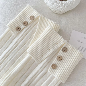 Detail of cream rib-knit leg warmers featuring vintage wooden buttons and soft texture