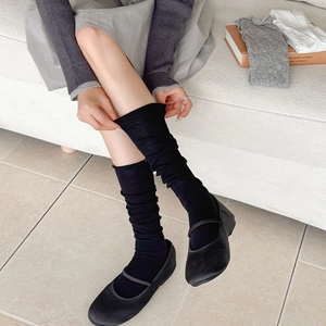 Detail of ballet style solid color split-toe calf socks worn with Mary Jane shoes