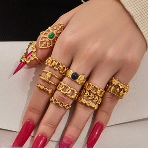 Detailed view of bohemian gold rings set with floral motifs and dark stones on hand