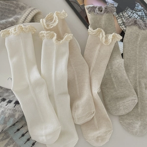 Empilement de chaussettes à côtes à volants blanc, beige et gris avec dentelle