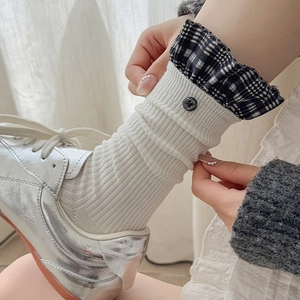 Detail of white ribbed crew socks with plaid ruffle trim and button styling on sneakers